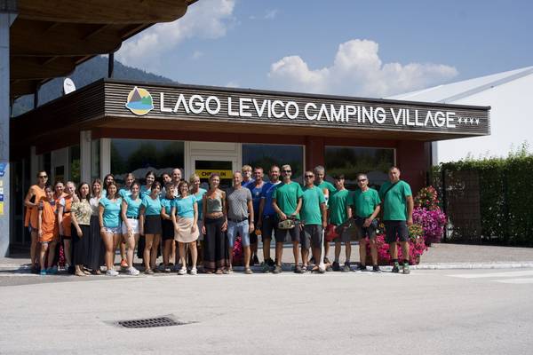 Teamfoto af Lago Levico Camping Village-personale foran receptionen.