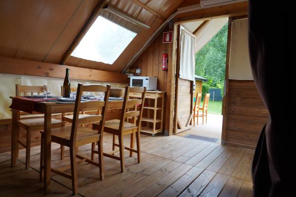 Indre udsigt af en campingtelt med bord, stole og mikrobølgeovn.