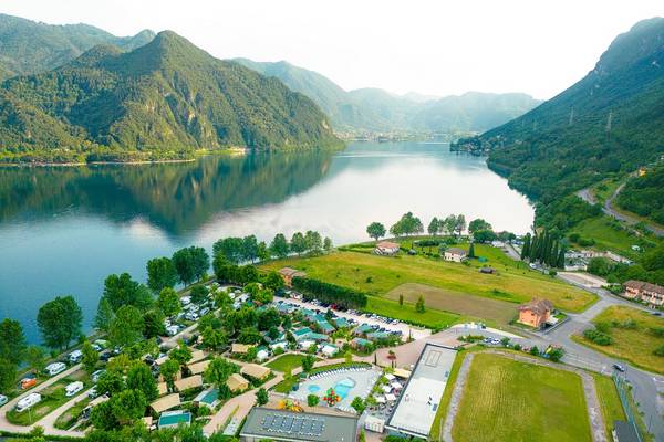Luftaufnahme vom Glamping-Campingplatz am Lago Idro mit Bergen, See und Gebäuden.