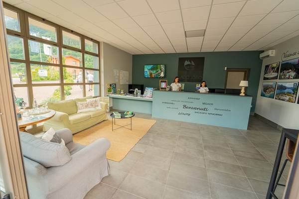 Espace d'accueil du camping Lago Idro Glamping Boutique avec deux membres du personnel derrière le bureau.