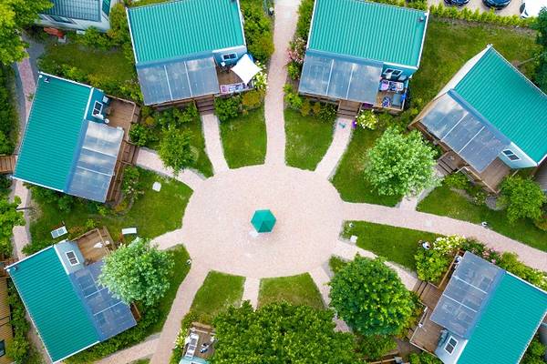 Vue aérienne du camping Lago Idro Glamping Boutique avec des toits verts et des panneaux solaires.