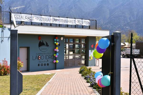 Entrée avant du camping Lago Idro Glamping Boutique avec des ballons et des montagnes en arrière-plan.