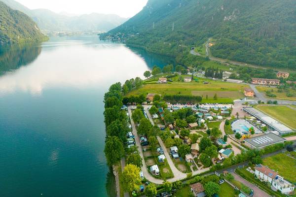 Vue aérienne du camping de glamping Lago Idro avec un lac, des montagnes et des villas.