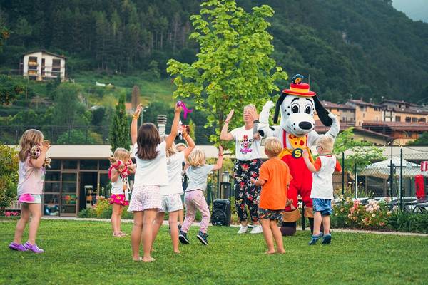 Enfants jouant avec des chiens et un mascotte sur un terrain de jeu