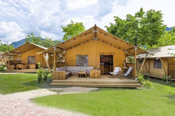 Trois tentes glamping au camping Lago Idro Glamping Boutique avec des sièges extérieurs et une terrasse en bois.