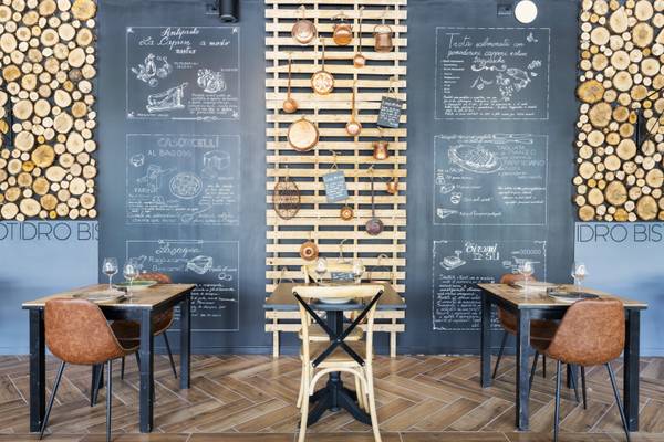 Vue intérieure d'un restaurant avec menu au tableau noir et revêtement mural en bois.