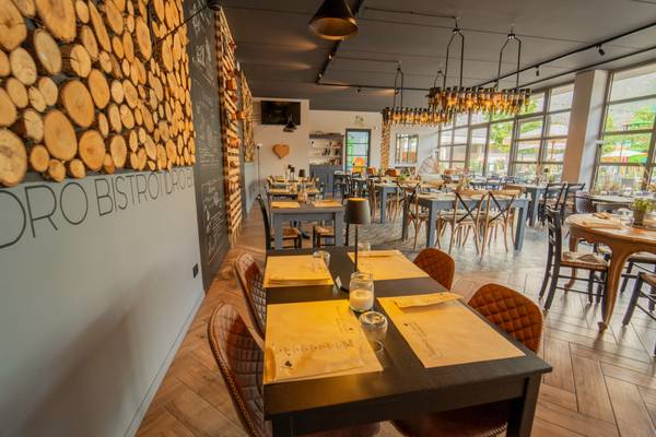 Intérieur du restaurant du camping Lago Idro Glamping Boutique avec des bûches en bois, des tables et des chaises.