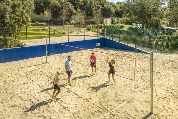 Quatre personnes jouant au volleyball sur un terrain de sable au Camping Vestar.