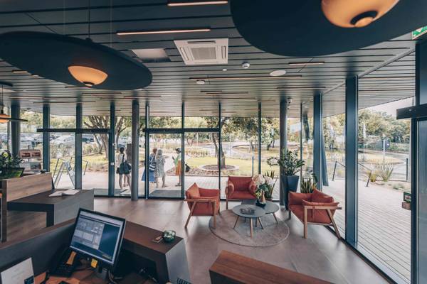 Espace réception du Camping Vestar avec mobilier moderne, murs en verre et vue sur les gens qui marchent dehors.