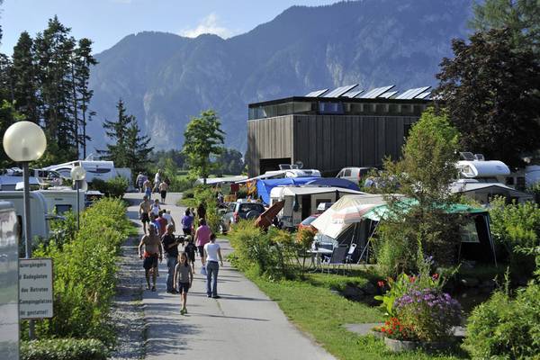 Campingplatz mit Menschen, die gehen, Berge im Hintergrund.