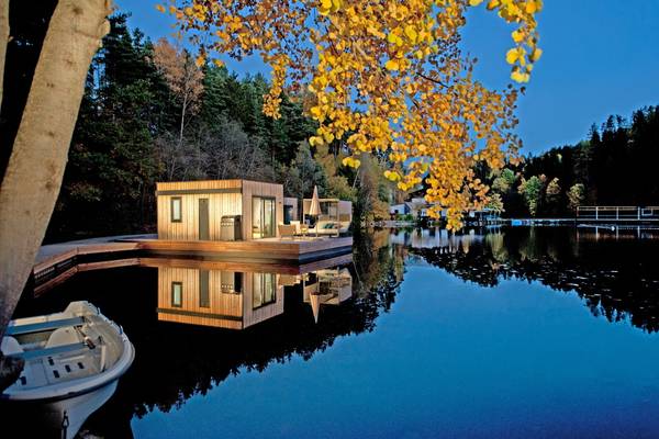 Ein holzhausboot im Ferienparadies Natterer See Campingplatz mit einem Boot auf dem Wasser und Bäumen im Hintergrund.