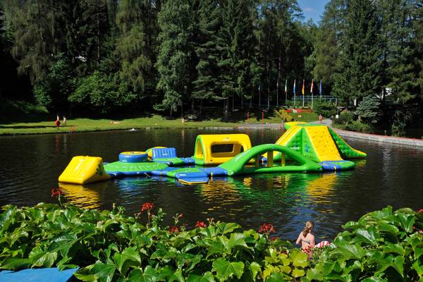 Wasserspielplatz im Ferienparadies Natterer See mit aufblasbaren Rutschen und Hindernissen.