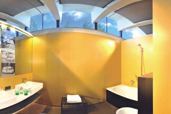 Campingdusche und Badezimmer im Ferienparadies Natterer See mit gelber Wand, zwei Waschbecken und Badewanne.