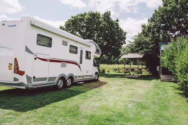 RV parkeret på en campingplads med hytte og picnicbord i nærheden.
