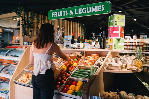 Kvinde i supermarkedet ved grøntsags- og frugtstand.