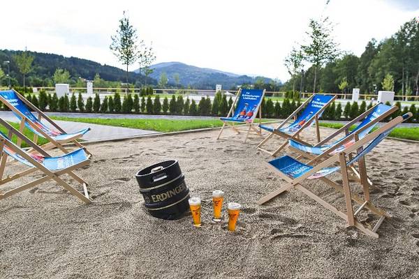 Udendørs loungestole i Camping Resort Bodenmais med ølglas og et tønde i sandet.