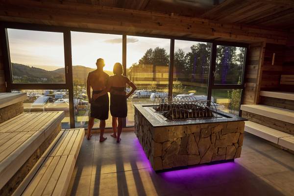 Twee mensen in een sauna in Camping Resort Bodenmais, kijken uit het raam.