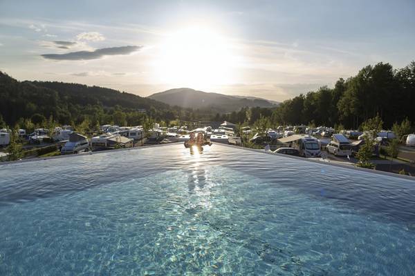Solnedgang på Camping Resort Bodenmais med stor pool og parkerede autocampere.