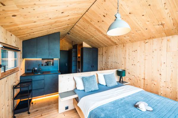 Interior de un dormitorio de madera en Alpencamping Nenzing con cama, almohadas y lámpara