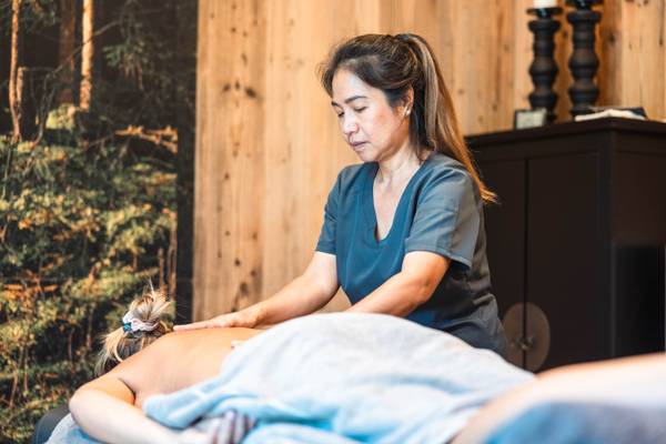 Una mujer en uniforme azul da un masaje en el área del spa de un hotel.