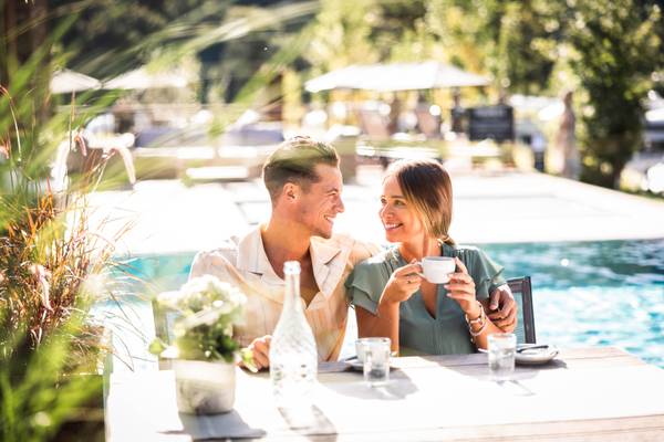 Una pareja disfruta del desayuno junto a la piscina en un hotel.