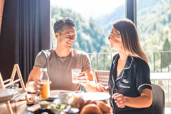 Desayuno en la ventana en Alpencamping Nenzing, una pareja sonriendo y disfrutando de su comida.