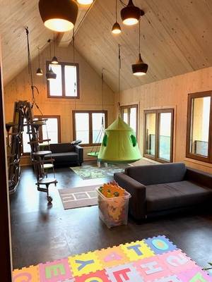Habitación infantil en el Alpencamping Nenzing con paredes de madera, dos sofás, una hamaca verde y juguetes.