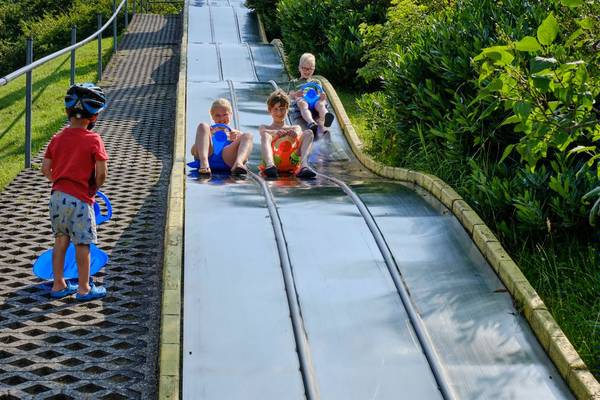 Kinderen glijden op een metalen glijbaan in het Europacamping Nommerlayen