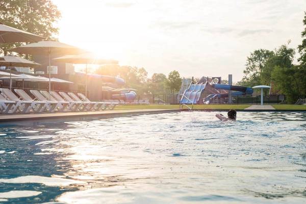 En person svømmer i en pool på Vakantiepark De Twee Bruggen camping ved solnedgang.