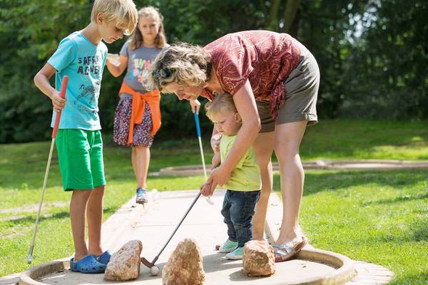 Familie spiller minigolf på campingpladsen.