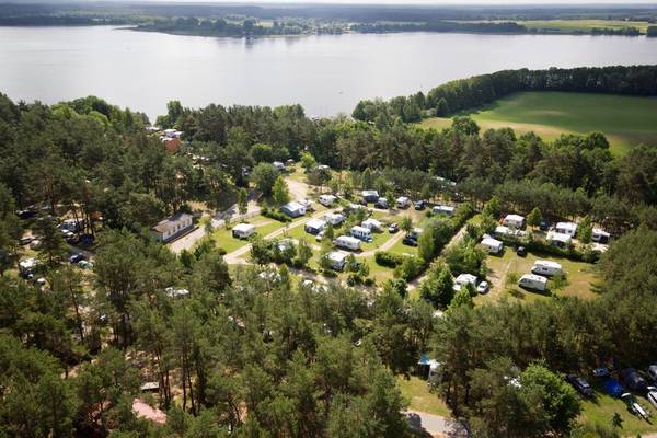 Aerial view of Camping- und Ferienpark Havelberge with many campsites by a lake.
