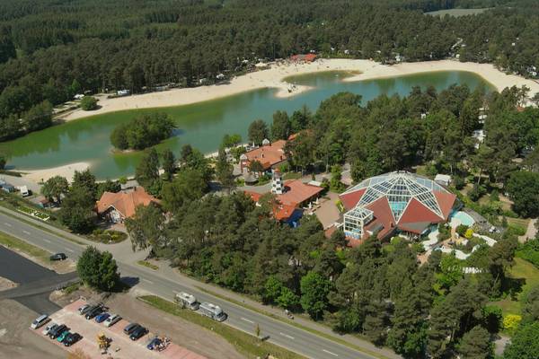 Luftfoto af Sudsee-Camp med bygninger, strand og sø.