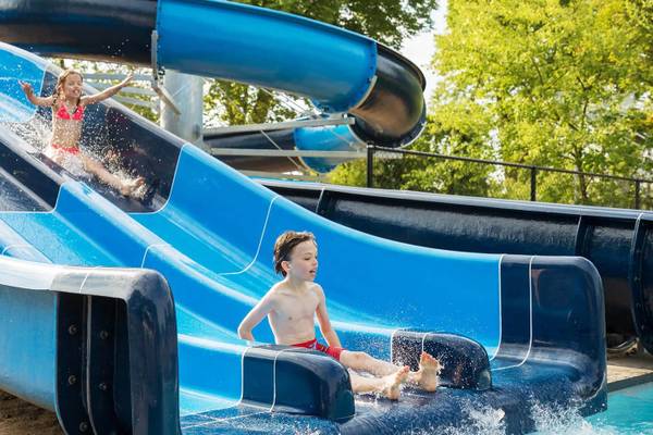 Børn glider ned ad blå vandrutsjer under himlen på Vakantiepark De Twee Bruggen
