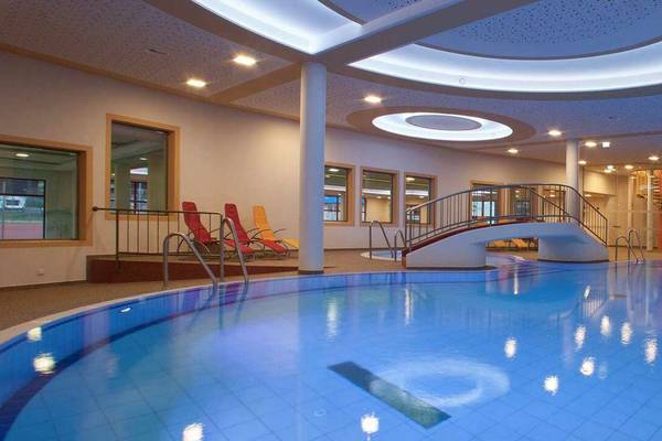Indoor pool at Erlebnis Resort Aufenfeld with a slide and lounge chairs.
