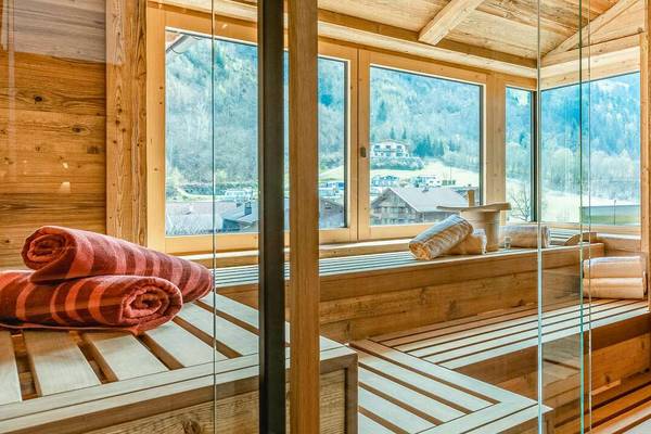 Interior of a wooden sauna with glass walls, wooden benches, and towels.