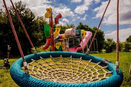 Schommel en glijbaan in het buitenspeelpark van Europacamping Nommerlayen