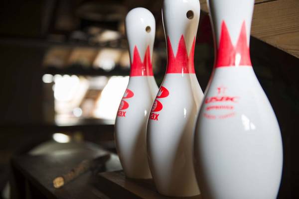 Drie bowlingpins met rode markeringen op een houten tafel in Europacamping Nommerlayen.