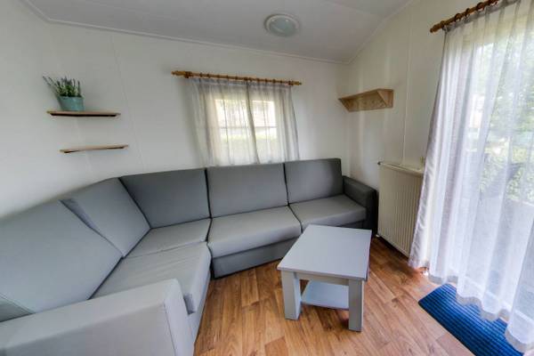 Interieur van een camping met een grijze bank, salontafel en houten vloer.