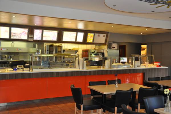 Interieur van het restaurant in Europacamping Nommerlayen met een rode balie en zwarte stoelen.