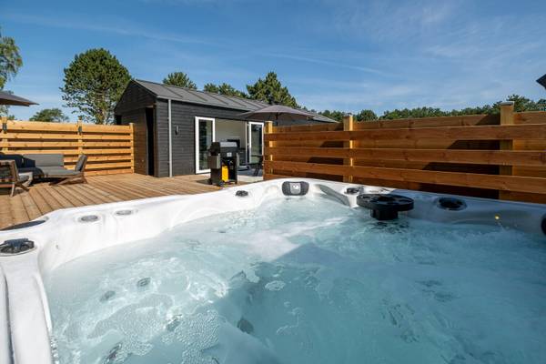 Jacuzzi al aire libre en el camping Feddet Strand Resort con terraza de madera y valla.