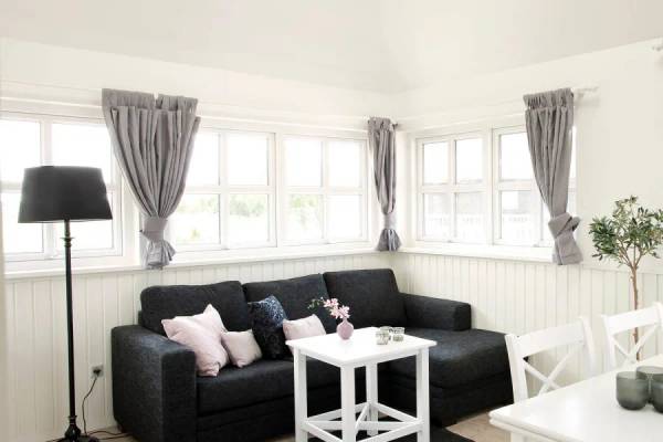Wohnzimmer im Hvidbjerg Strand Feriepark mit schwarzem Sofa und weißen Möbeln.