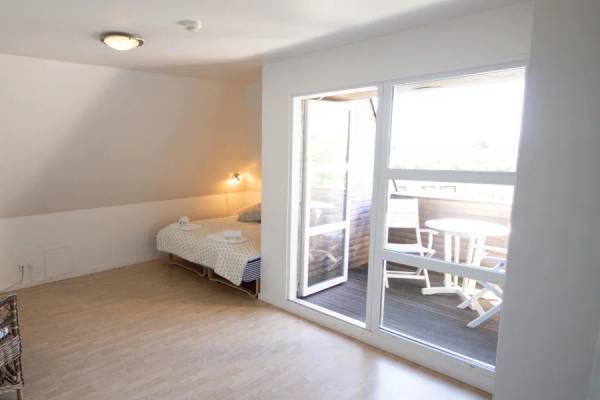 Innenansicht eines Zimmers im Hvidbjerg Strand Feriepark mit Bett, Stühlen und Balkon.