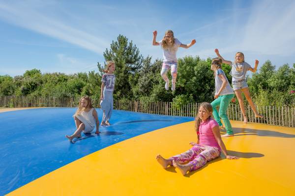 Kinder springen auf einem großen Seiltanz im Freien.