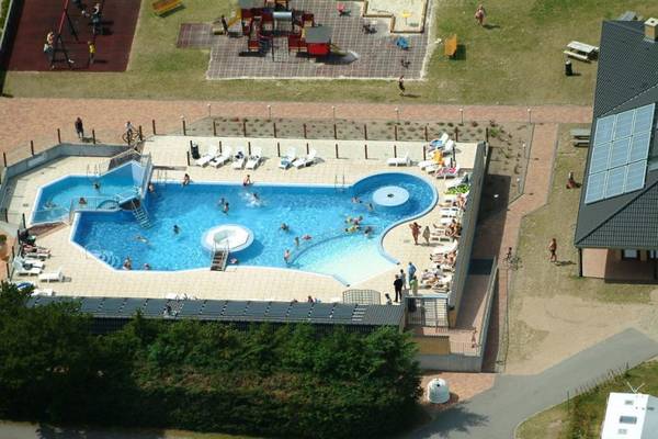 Vista aérea de un camping con una piscina y personas nadando.