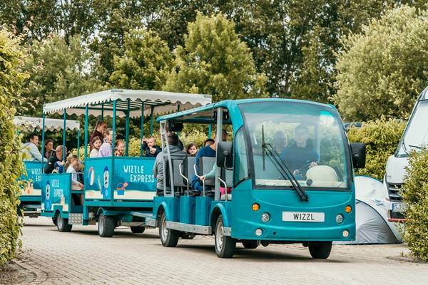 Blaue Wizzl Express Fahrt im Campingplatz mit Kindern und Erwachsenen an Bord.