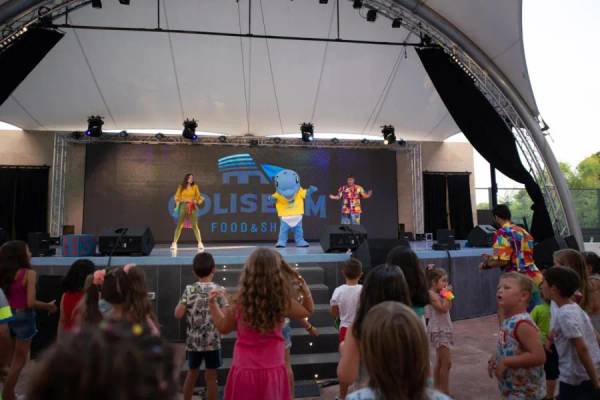 Des enfants regardent une performance avec des mascottes sur une scène au Camping La Marina.