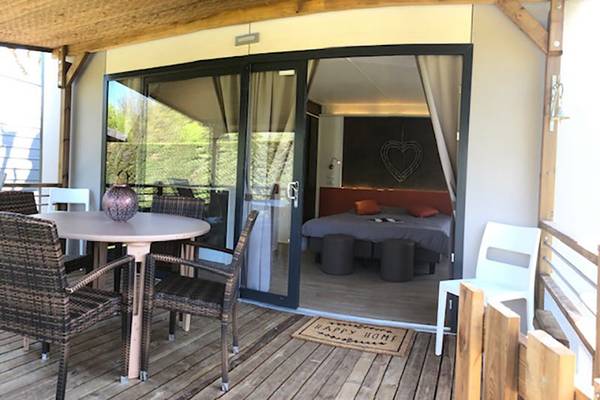 Terraza con mesa y cama en el camping Nature Parc L`Ardéchois