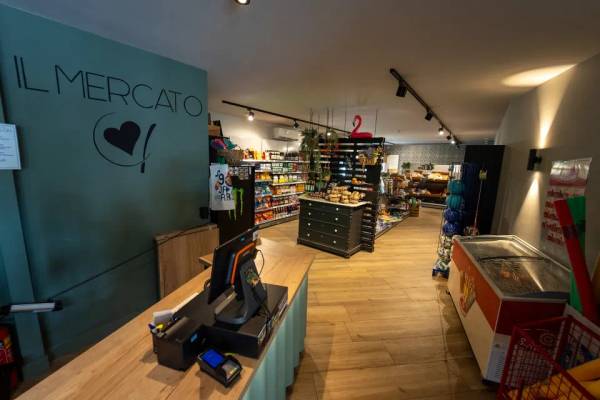 Vista interna del supermercato Il Mercato con pavimento in legno e vari prodotti in esposizione.