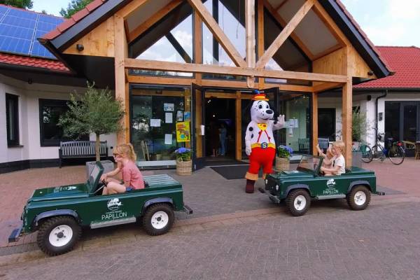 Bambini in auto giocattolo con il mascotte davanti al Papillon Country Resort.