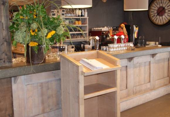 Innenbereich einer Campingbar mit Blumenarrangement und einer Frau an der Theke.